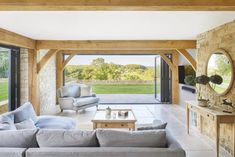 a living room filled with furniture next to a large open door leading to a lush green field