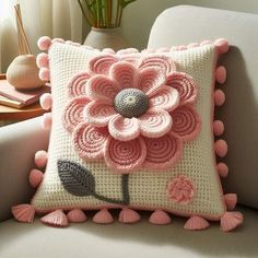 a crocheted flower pillow sitting on top of a couch