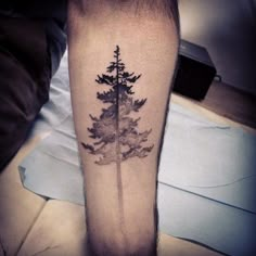 a person with a tattoo on their leg that has a pine tree in the middle