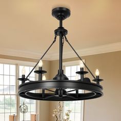 a black chandelier hanging from the ceiling in a room with windows and furniture