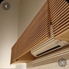 a white air conditioner sitting on top of a wooden shelf above a tiled wall