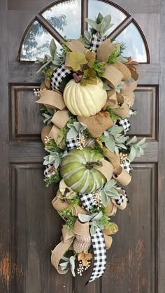 a wreath with pumpkins and greenery hangs on the front door