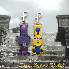 two key chains with cartoon characters on them sitting on some steps in front of a building