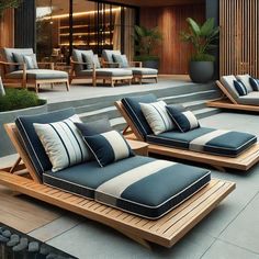 two chaise lounges with blue and white pillows on top of them in front of a building