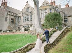 a bride and groom walking up the stairs to their wedding ceremony venue in front of an old castle