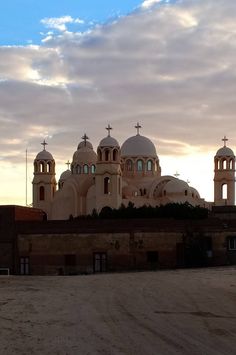 an old building with three crosses on it's roof and two bell towers in the background