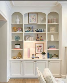 a living room filled with lots of furniture and bookshelves on top of white shelves