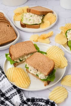 two plates with sandwiches and chips on them