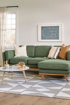 a living room with a green couch and coffee table in front of a large window