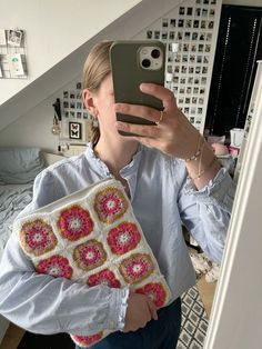 a woman taking a selfie with her cell phone and crocheted granny bag