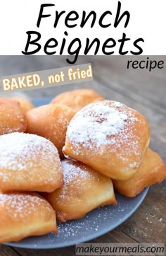 a blue plate topped with sugar covered doughnuts on top of a wooden table