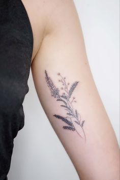 a woman with a tattoo on her arm has a fern branch in the middle of her arm