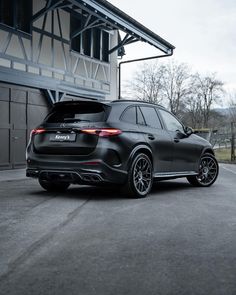 the rear end of a black mercedes suv parked in front of a building with its trunk open