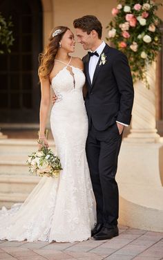 a bride and groom pose for a photo in front of an archway with flowers on it