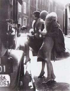 an old photo of three women standing on the sidewalk