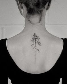 the back of a woman's neck with a small pine tree tattoo on it