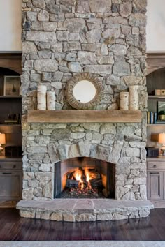 a stone fireplace in a living room with wood flooring