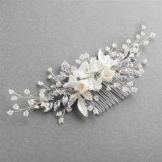 a bridal hair comb with flowers and pearls on the headpiece is laying on a gray surface