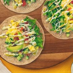 three tortillas topped with veggies and cheese on a wooden cutting board