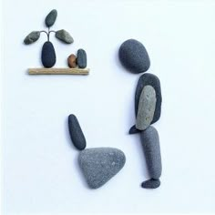 some rocks are arranged in the shape of people and one is holding a branch with leaves