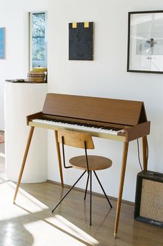 a piano sitting on top of a hard wood floor next to a wall with pictures above it