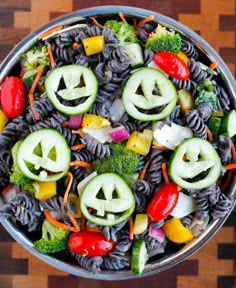 a bowl filled with pasta, vegetables and jack - o'- lanterns carved into faces