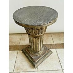 a round wooden table sitting on top of a tiled floor