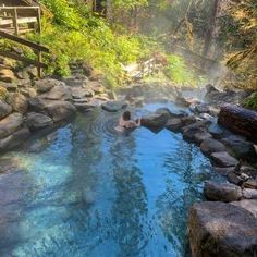 two people swimming in a hot spring surrounded by rocks