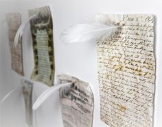 two pieces of paper with writing on them and a feather hanging from the wall next to each other