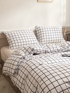 an unmade bed with black and white checkered comforter on the bottom half