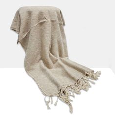 a blanket with tassels on it sitting on top of a table