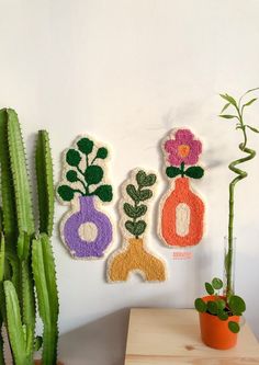 three felt flowers are hanging on the wall next to a potted succulent