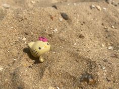 a hello kitty figurine in the sand with a pink bow on it's head