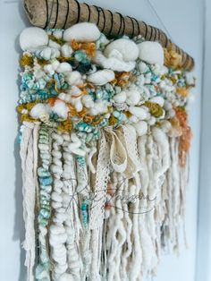 a close up of a wall hanging made out of yarn and beads with shells on it