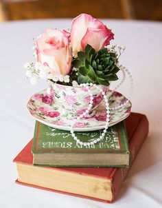 three roses in a teacup on top of two books