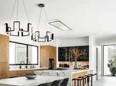 a modern kitchen with marble counter tops and wooden cabinetry, along with black bar stools