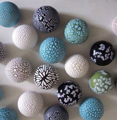 an assortment of different colored and black and white balls on a counter top, with one ball in the middle surrounded by smaller ones