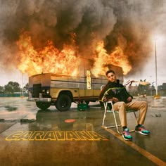 a man sitting on a chair in front of a truck with flames coming out of it