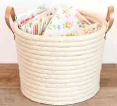 a white basket filled with lots of papers on top of a wooden table