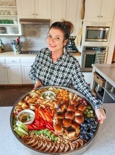 a woman holding a large platter of food