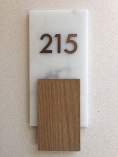 the number twenty five is mounted to the wall with a wooden block in front of it