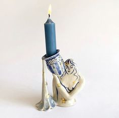 a blue candle is sitting on top of a ceramic elephant with a vase in the shape of an elephant