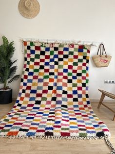 a multicolored blanket sitting on top of a wooden floor next to a potted plant