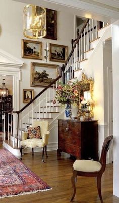 a living room filled with furniture and pictures on the wall next to a stair case