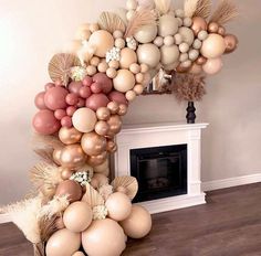 balloons are arranged in the shape of an arch with flowers and leaves on it, near a fireplace