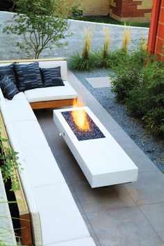 an outdoor patio with fire pit and couches on the ground, surrounded by plants