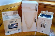 three wooden toy kitchen appliances sitting on top of a wood table next to each other