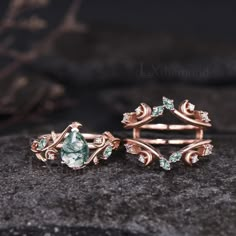 two rings with green and white stones on top of a stone slab in front of a black background