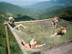 four people laying in a hammock on top of a mountain