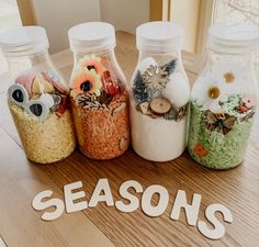 four jars filled with different types of food sitting on top of a wooden table next to the word season's written in white letters